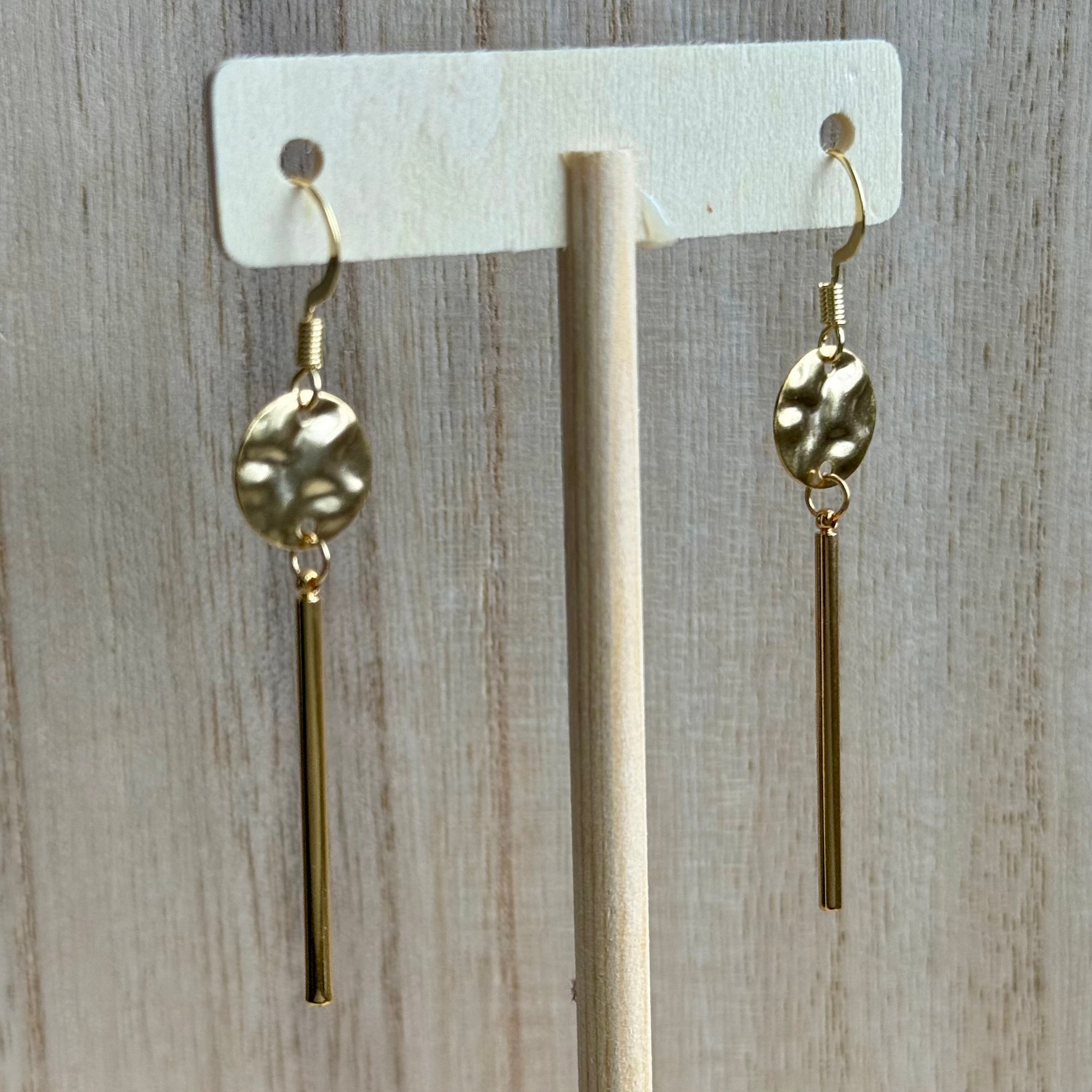 Gold hammered disc with dangle bar.